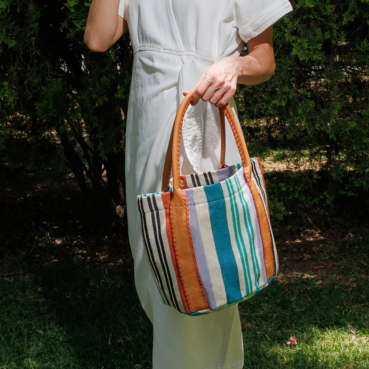 Handmade woven straw bag with leather handles on a wooden table